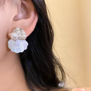 Detailed close-up of elegant shell and pearl stud earring with iridescent finish