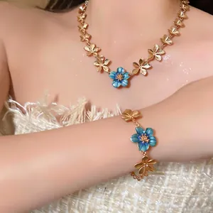 Elegant gold-toned necklace and bracelet jewelry set featuring blue enamel flower charms