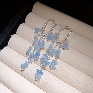 Primo piano di orecchini a nappa d'argento con frammenti di pietra blu e strass.