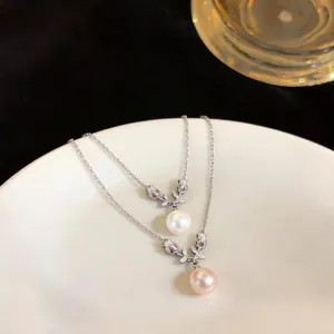 Elegant zircon flower pearl pendant necklace set displayed on a white ceramic plate backdrop