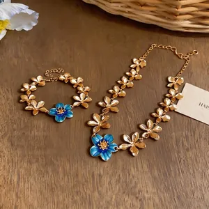 Elegant gold-tone necklace and bracelet set featuring delicate blue enamel flower charms