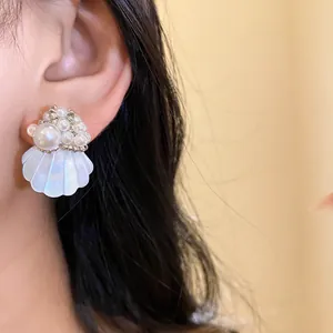 Detailed close-up showing white beaded flower and shell earrings worn on an ear