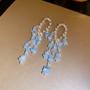 Dettaglio ravvicinato di orecchini in argento con strass scintillanti e nappine in pietra blu