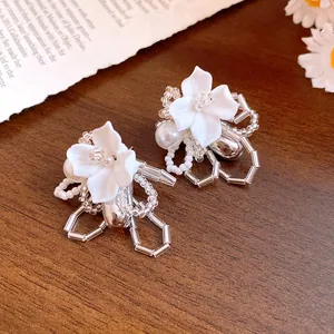 Close-up of elegant handmade white gardenia flower beaded earrings with delicate pearl accents.