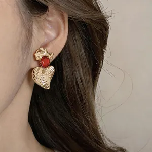 Dettaglio di orecchini vintage in oro martellato con gemma in resina rossa su modella