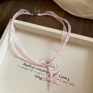 Dettaglio della collana con stella marina in resina rosa e nastri in organza.