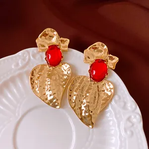 Primo piano di orecchini vintage a foglia d'oro con resina rossa su un piatto bianco decorato