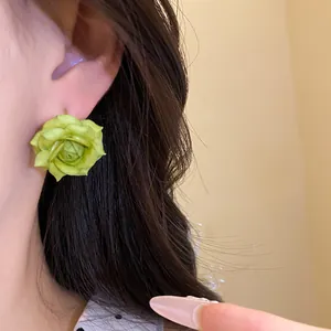 Vista ravvicinata di un orecchino a bottone a forma di rosa verde indossato sull'orecchio