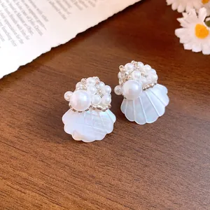 Detail view of vintage-style shell stud earrings with white pearl bead clusters