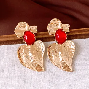 Primo piano di orecchini vintage a foglia d'oro con grandi pietre di resina rossa su tela chiara