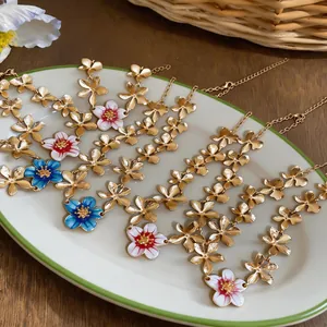Close-up detail of elegant gold enamel flower necklaces on a white decorative plate