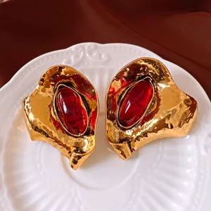 Primo piano di orecchini vintage in oro martellato con grandi pietre in resina rossa