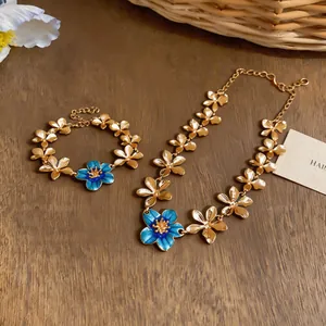 Detailed view of the blue enamel flower necklace and matching bracelet set
