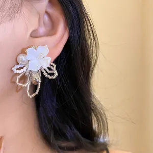 Close-up view of elegant white gardenia flower beaded earrings with delicate pearl accents