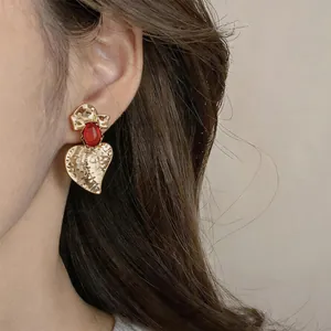 Primo piano di orecchini vintage a foglia d'oro con elegante intarsio in resina rossa