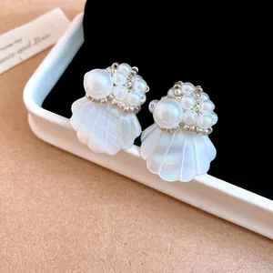 Detailed view of iridescent shell stud earrings with white pearl bead accents