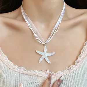 Primo piano della collana con ciondolo a stella marina in resina bianca e nastro