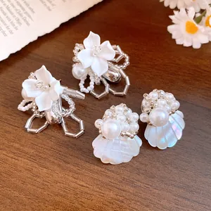 Close-up of white gardenia and iridescent shell beaded stud earrings on wood