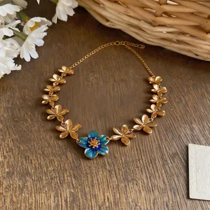 Detailed view of the gold-plated flower necklace with a central blue enamel blossom