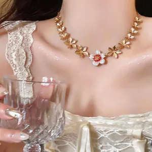 Detailed view of an elegant gold necklace featuring a central white enamel flower pendant