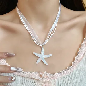 Dettaglio di una collana con ciondolo a stella marina in resina bianca indossata da una modella