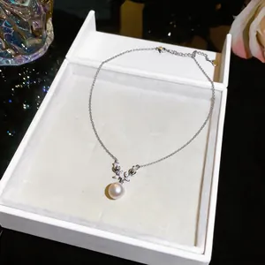 Detailed shot of elegant pearl pendant necklace with zircon floral accents in white gift box