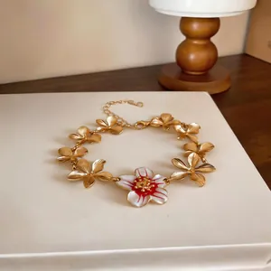 Detail of a gold flower bracelet with a white and red enamel centerpiece