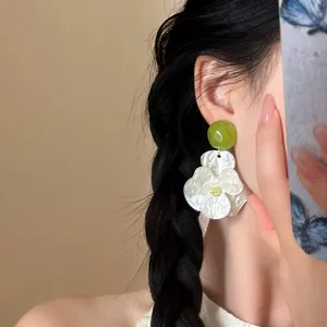 Close-up of white gardenia blossom earrings with green bead on an Asian model