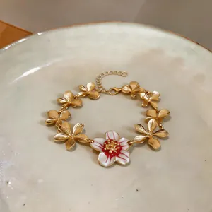 Detailed close-up showing the textured petals and red enamel flower of this gold bracelet