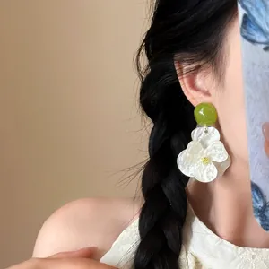 Detailed close-up of large white gardenia flower earrings worn by an Asian fashion model