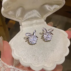 Elegantes pendientes de botón con lazo y cristales brillantes en caja concha