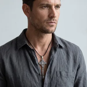 Detailed close-up of an ornate vintage key pendant worn by a male model in a grey shirt.