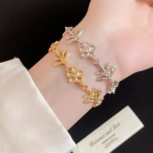 Dettaglio di eleganti bracciali in oro e argento con motivi floreali indossati al polso