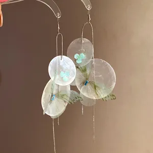 Macro detail of Mori style earrings with chiffon butterfly wings and shell flower accents