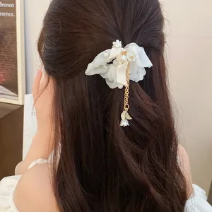 Dettaglio dell'elastico in organza bianca con perle e nappa a foglia sui capelli