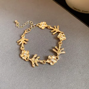 Vista dettagliata di un bracciale dorato con delicati fiori e motivi a ramo elegante.