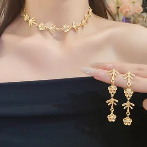 Primo piano dell'elegante set collana e orecchini a fiore in metallo dorato su modella