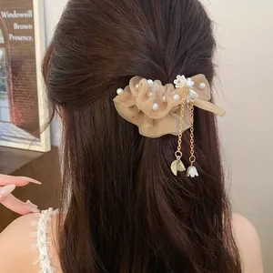 Scrunchie in chiffon beige con perle e nappa floreale su lunghi capelli castani vista