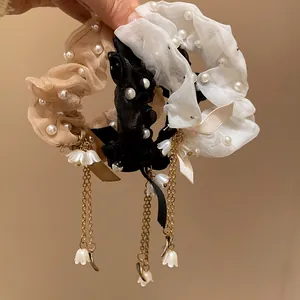 Dettaglio di eleganti elastici in organza con perle e nappe a fiore pendenti chic.