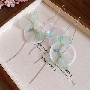 Macro view of forest style chiffon butterfly earrings featuring delicate shell discs and tassels