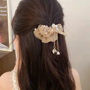 Dettaglio elastico per capelli in chiffon beige con perle e nappe lunghe dorate.