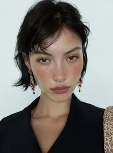 Close-up of vintage court style resin floral earrings with red crystal drops on a model