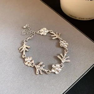 Dettaglio di bracciale argento con fiori e rami irregolari, finitura metallica testurizzata