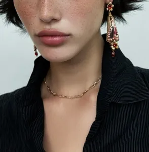 Close-up of vintage European court style resin dangle earrings and gold chain necklace