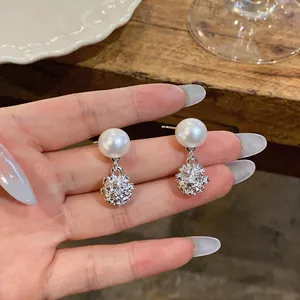 Detalle en primer plano de pendientes de perlas estilo francés con colgantes de plata.