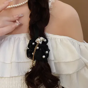 Dettaglio dell'elastico per capelli in garza nera con perle e nappe a fiore d'oro