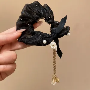 Primo piano di elastico per capelli in organza nera con perle e nappa con fiori e foglie