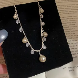 Detailed view of a silver necklace with pearls and zircons displayed on a black velvet block.