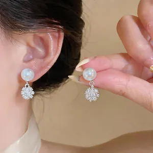 Vista detallada de pendientes de perlas con esferas de diamantes brillantes.