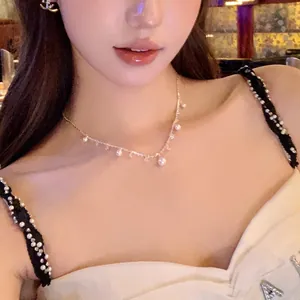 Close-up of a delicate pearl and zircon necklace worn by a model in warm light